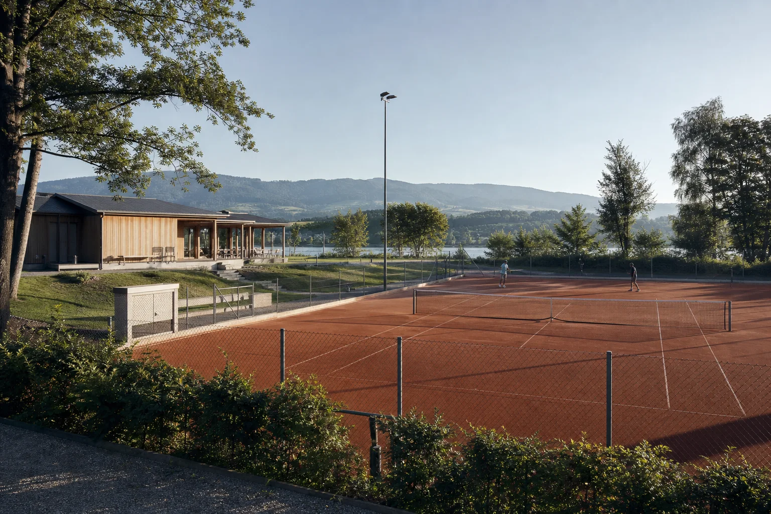 Lokaler Tennisclub mit Sandplätzen, Clubhaus und See am frühen Morgen